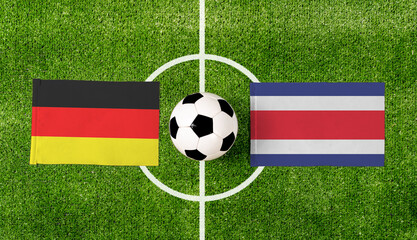 Top view soccer ball with Germany vs. Costa Rica flags match on green football field.