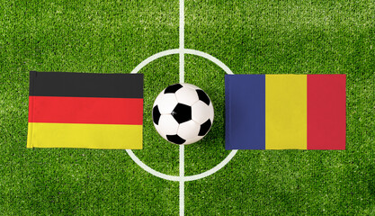 Top view soccer ball with Germany vs. Romania flags match on green football field.