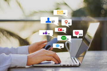 Close up of businessman hands at desk using laptop and smartphone with creative social media icons on abstract blurry outdoor background. Like, network, technology and communication concept.