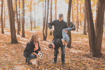 Naklejka na ściany i meble Family spend time in autumn park with a dog. Father, mother and daughter and jack russell terrier dog having fun in fall
