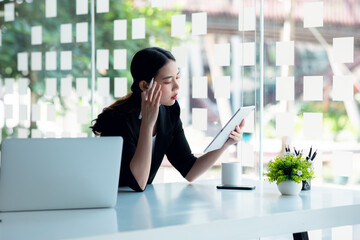 Fototapeta premium Portrait of Young Asian Businesswoman working on laptop computer doing finances, accounting analysis, report, data and pointing graph at the office.