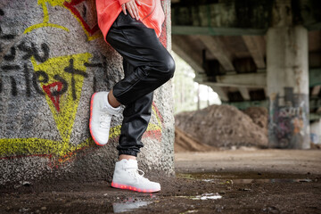 Girl standing under bridge and wearing modern LED shoes