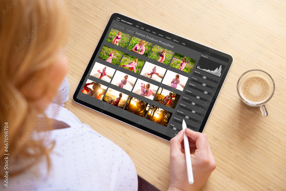 Wall mural woman working with digital photo files library and editing photos on tablet computer