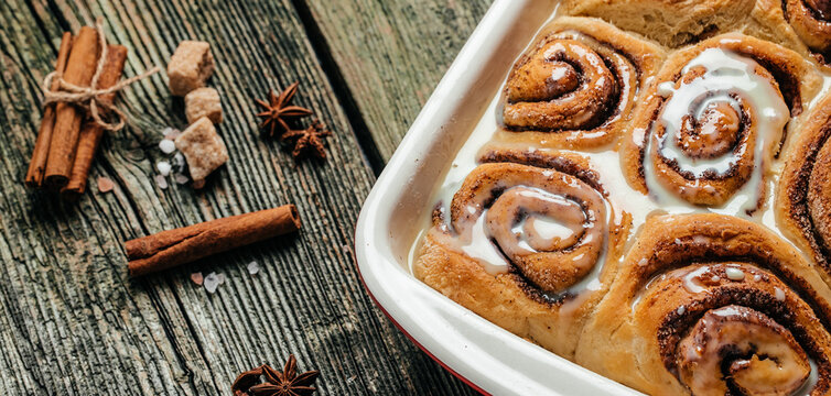 Cinnamon rolls with white cream sauce. Long banner format. top view