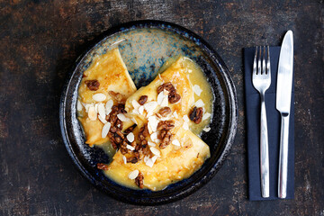 Pancakes with cheese in orange sauce served with caramelized nuts and almonds.
Appetizing dish. Culinary photography, a proposal to serve a meal.