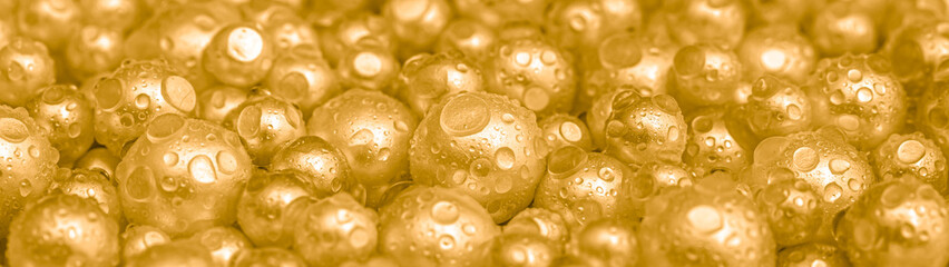 Beautiful background with pearl gold pearls, top view. Abstract texture for festive backgrounds. Shiny yellow surface of Christmas decorations. Gems close-up. Golden bright background.