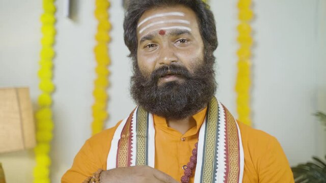 Indian god man or saint preaching holy vedas by looking camera at monastery - concept of religious teachings by monks at temples.