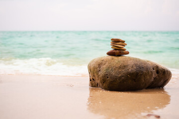 Stack pyramid stone zen pebbles nature on big rock at coast with blur blue sea background. meditation tranquil calm still balance relax of buddhism religion or tropical travel summer holidays concept.