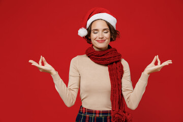 Young woman wear Christmas red hat hold spreading hands in yoga om aum gesture relax meditate try...