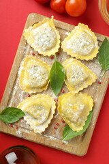 Concept of cooking ravioli on red background