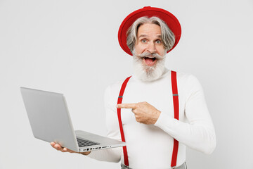 Elderly gray-haired mustache bearded man 50s in turtleneck red hat suspenders hold use work point...
