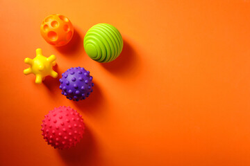 Multicolored rubber massagers for children, on an orange background, place for an inscription