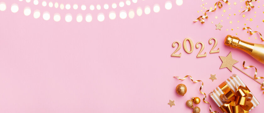 Champagne bottle, golden gift or present box, 2022 number and confetti on pink background top view. Christmas and New Year greeting card. Flat lay.