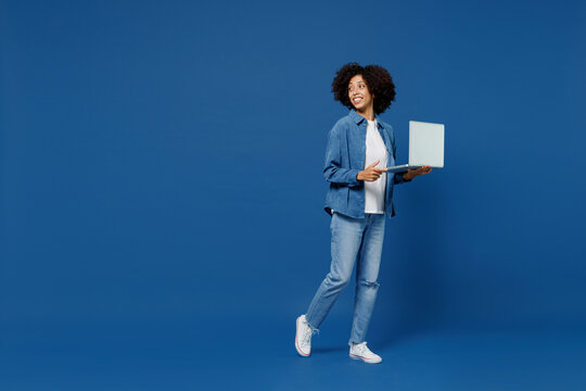 Full Body Young Smiling Happy Black Woman In Casual Clothes Shirt White T-shirt Hold Use Work On Laptop Pc Computer Look Aside Isolated On Plain Dark Blue Background Studio. People Lifestyle Concept.