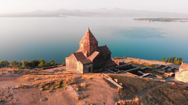 Aerial zoom out view Sevanavank armenian monastery complex in Sevan city with blue lake panorama at sunrise . Famous landmark sightseeing in caucasus. Armenia travel concept