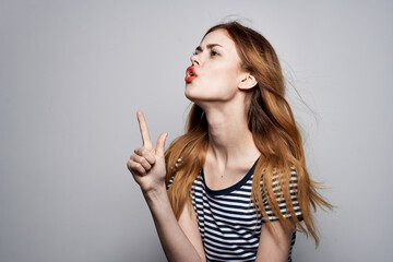 Obraz premium pretty woman in a striped t-shirt gesture with his hands light background