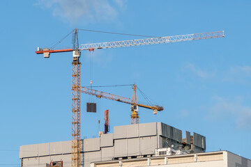 Two tower cranes on the construction of a high-rise building. Lifting mechanisms. Lifting of loads and building materials