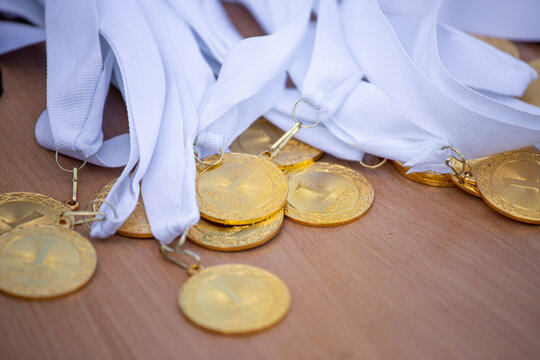 A Bunch Of Gold Medals On A White Ribbon For First Place In Sports Competitions.