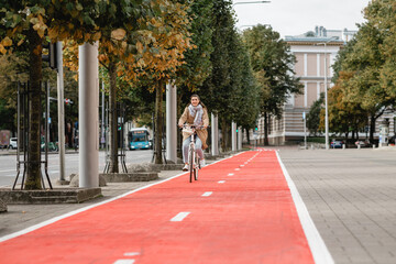 traffic, city transport and people concept - happy smiling woman riding bicycle along red bike lane...
