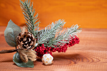 One single D20 role playing white dice on a gaming table made of wood stay near Christmas tree. Dungeons and Dragons role-playing games