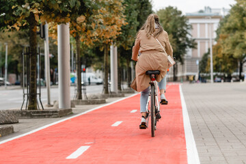traffic, city transport and people concept - woman riding bicycle along red bike lane or two way road on street