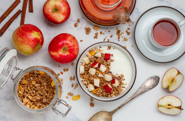 Homemade granola (muesli) with oatmeal, nuts, flaxseed, cornflakes, fresh red apple, cinnamon and yogurt 