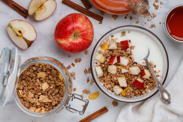 Homemade granola (muesli) with oatmeal, nuts, flaxseed, cornflakes, fresh red apple, cinnamon and yogurt 