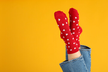 Female legs in socks with hearts and in jeans on yellow background