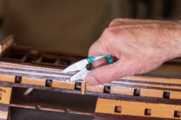 Old man working on creating a ship model