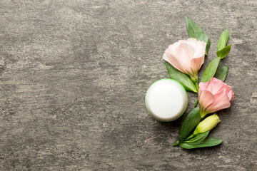 Composition with cosmetic products and beautiful roses on cement background. Copy space, flat lay