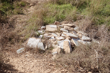 wantonly discarded building materials and a plastic bottle that were dumped illegally pollute a...