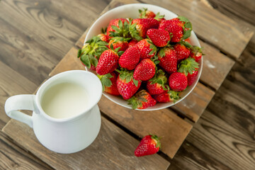 freshly picked organnic strawberry and milk on wooden table natural background, countryside, healthy eating. 