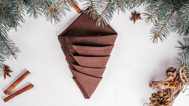 Step-by-step stop motion video tutorial: How to fold linen napkin in shape of Christmas tree. New Year table setting. Top view