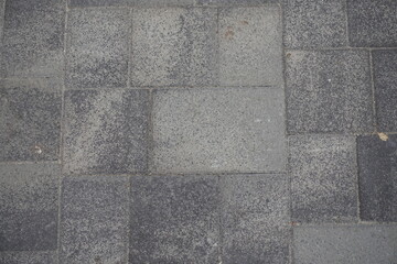 Top view of pavement made of rectangular gray concrete blocks