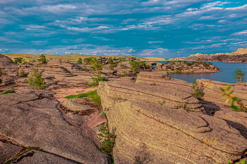 Beautiful nature of the lake and rocky mountains. Unusual landscape of nature. Trees among the rocks against the sky with clouds.