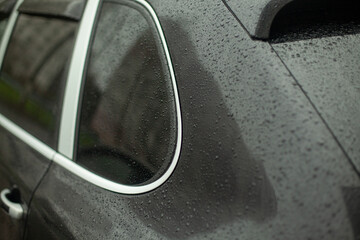 Drops on the car. Car parts in the rain. Small drops on a black surface.