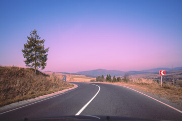 Fototapeta premium View of the mountain winding road from windscreen during sunrise