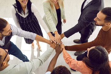 Smiling diverse business team stacking hands. Mixed race group of happy young people putting hands...