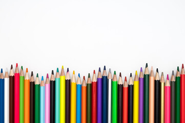 Back to school or creativity concept. Wavy frame made of colored crayons against white background. Table top view, flat lay, copy space.