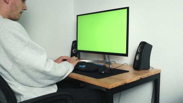 The guy works from home on a computer with a green screen. Work from home. A young freelancer uses a computer. High quality 4k footage