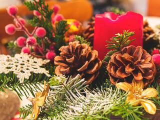Christmas season background with pine cones. fir tree branches and red candle and berries. New year and winter season holiday theme decorations. Selective focus