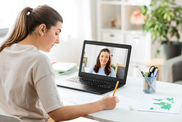 Fototapeta na wymiar education, online school and distant learning concept - student woman having video call or meeting with teacher on laptop computer and drawing picture of cat on paper at home