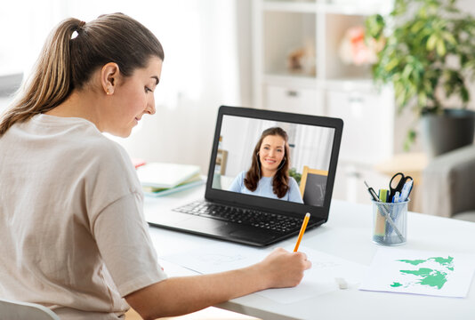 education, online school and distant learning concept - student woman having video call or meeting with teacher on laptop computer and drawing picture of cat on paper at home