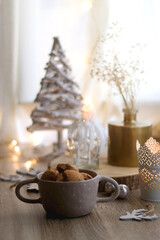 Bowl of cinnamon cookies, lit candles and various Christmas decorations on the table. Selective focus.