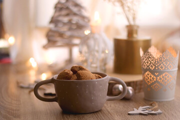 Bowl of cinnamon cookies, lit candles and various Christmas decorations on the table. Selective focus.