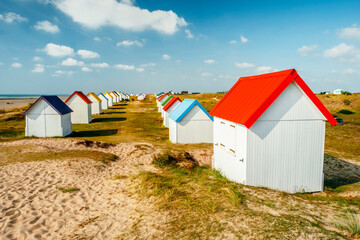 Fototapeta na wymiar Row of colorful huts on the dune beach of Gouville-sur-Mer, Lower Normandy, France