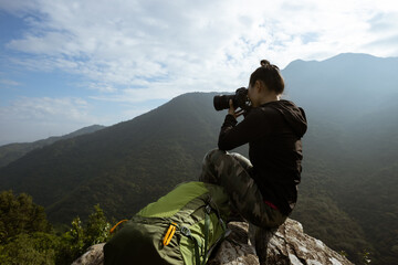 Successful hiker taking photo on sunrise mountain top cliff edge