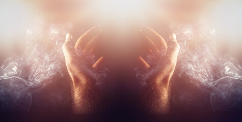hand in smoke ona black background, praying hands.