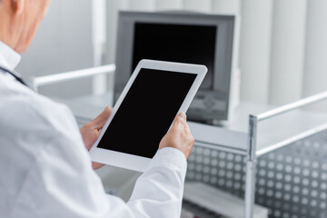 Cropped view of blurred doctor holding digital tablet with blank screen in hospital