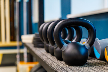 large black weights are arranged in a row. shelf with weights in the gym